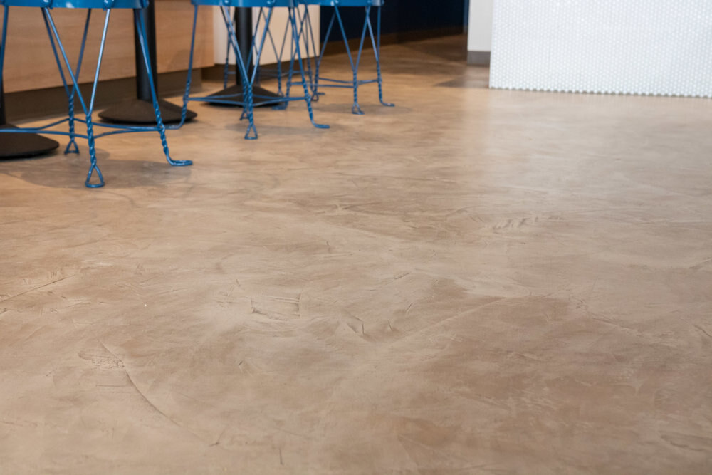 Warm mottled decorative concrete floor across a hospitality seating area
