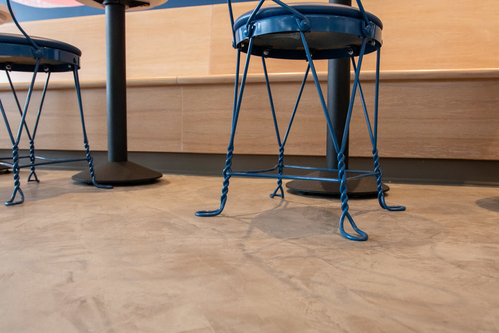 Decorative concrete floor meeting blue metal seating supports