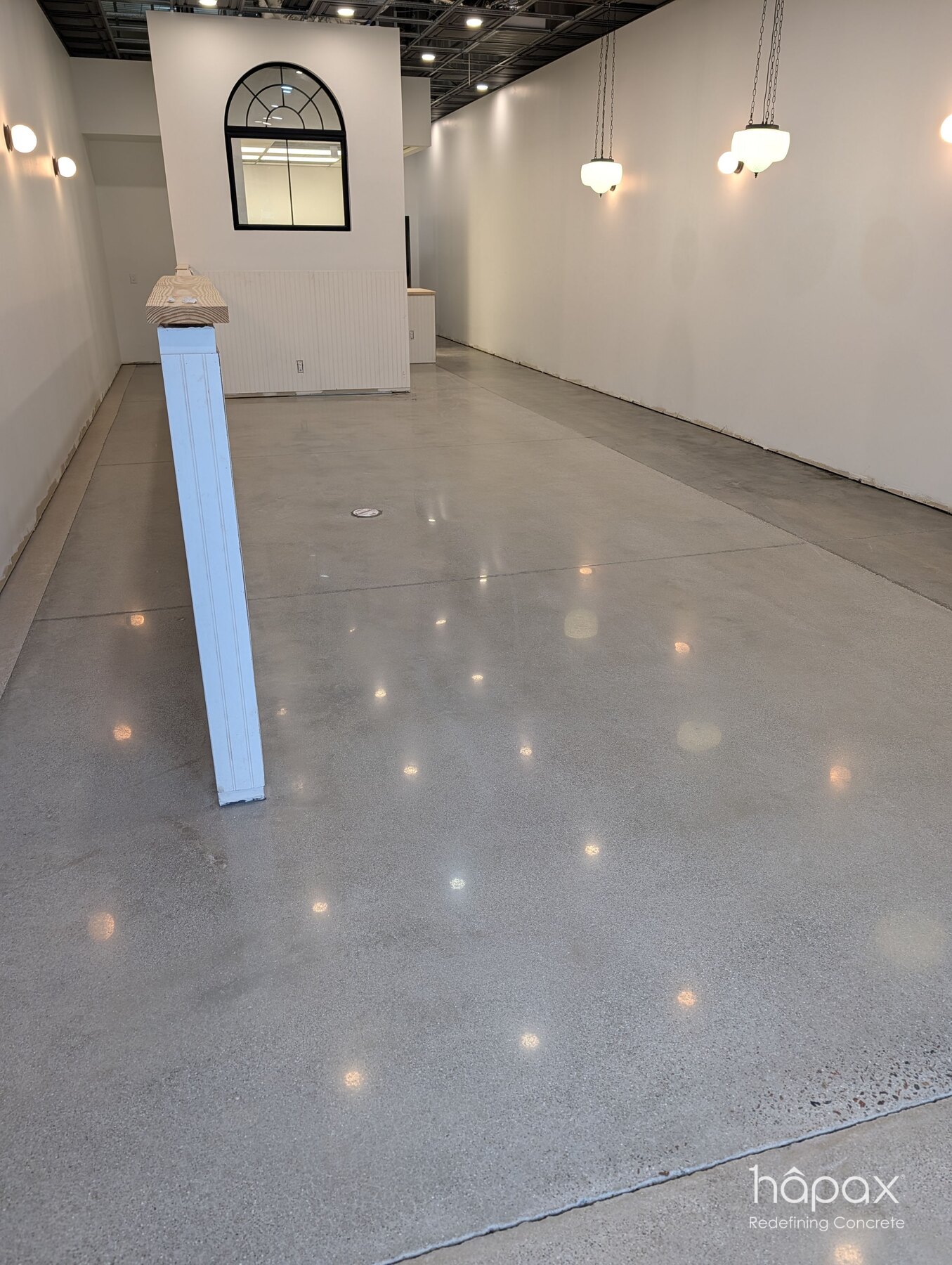 Polished concrete retail floor with fine aggregate exposure and reflected pendant lights at Lolly’s Great Bridge.