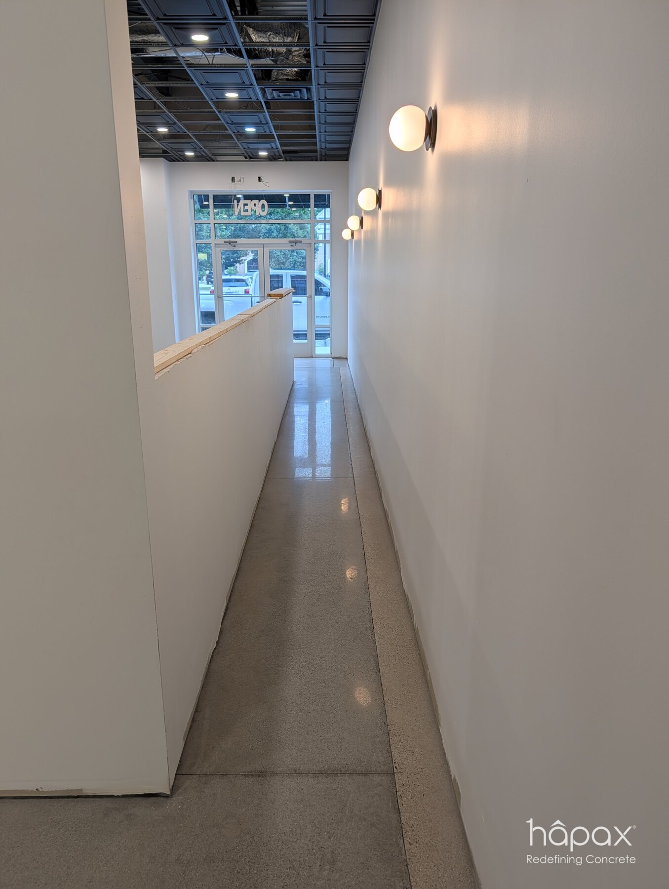 Polished concrete continuing through a narrow circulation corridor inside Lolly’s Great Bridge.